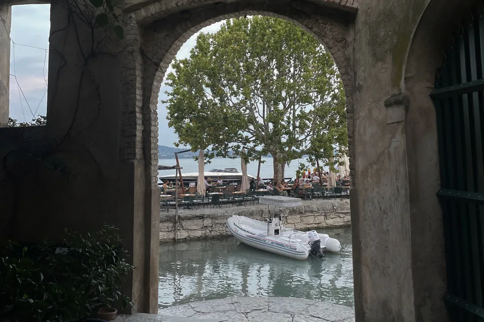A stone arch opening onto the lakefront and a plane tree